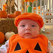 Camden is registered to the contest to win money with this photo: baby, pumpkin_costume, orange, fall, autumn, porch, decorations, pumpkin, hay, cute, child, face, costume, seasonal, holiday, outdoor, smile, festive, holiday_decoration, cozy