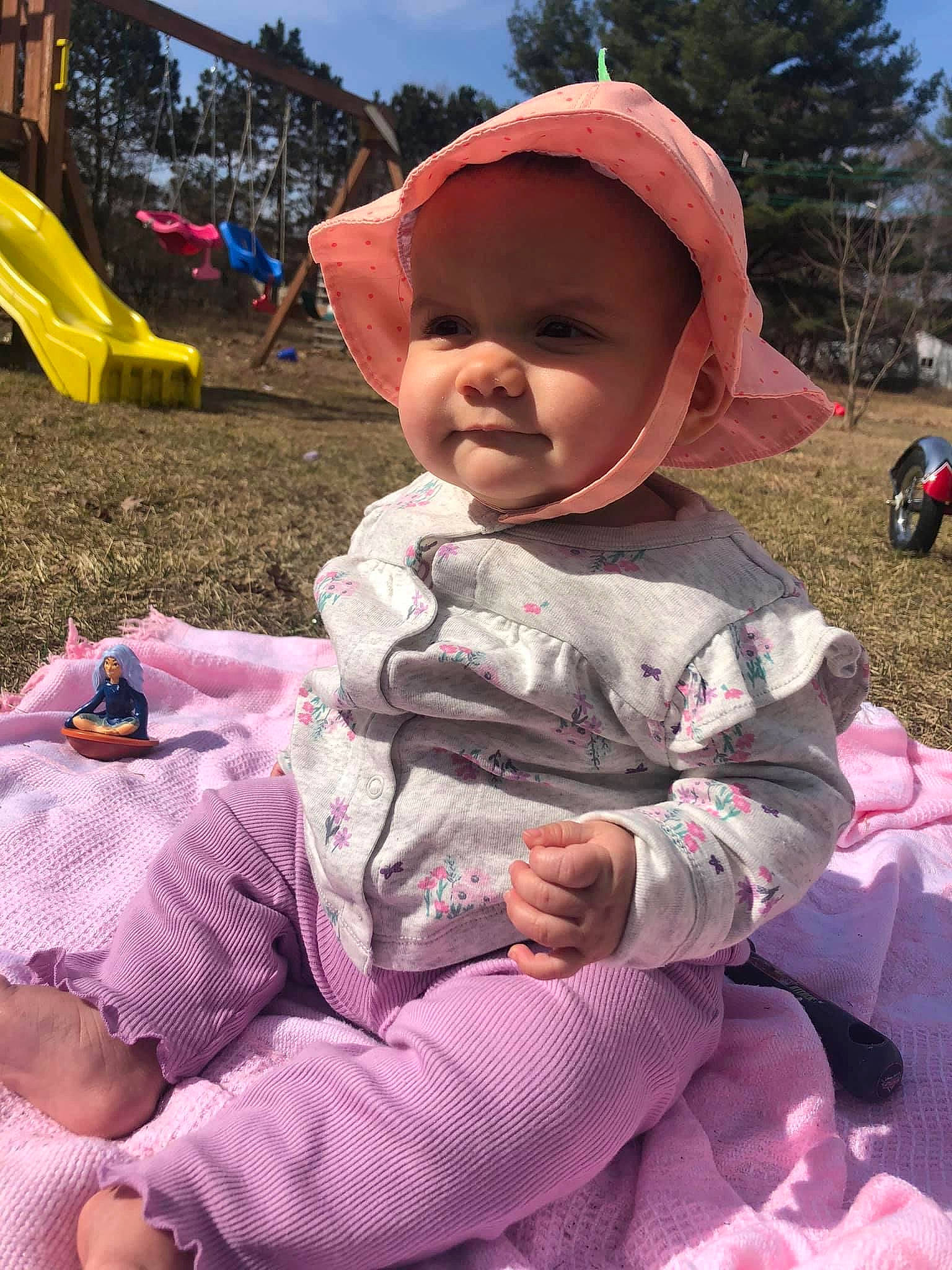 Ellianna is registered to the contest to win money with this photo: baby, baby_toddler_clothing, baseball_cap, cap, child, fun, grass, happy, hat, headwear, leisure, magenta, mouth, person, pink, recreation, sitting, skin, sky, smile