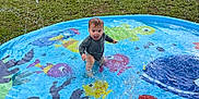 Ronan joined the competition — help win amazing prizes! car, child, colorful, daylight, fun, grass, happy, house, nature, outdoor, play, pool, recreation, sitting, splashing, sprinkler, summer, toddler, water, water_toys