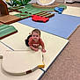 toddler, child, indoor_play_area, play_mats, soft_play, colorful_wall_mural, flower_mural, crawling, curious, padded_floor, toy_shapes, casual_clothing, short_hair, carpet, door, wall, playground, baby, floor, safe_environment