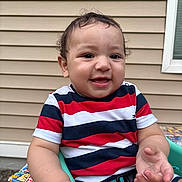 Michael is registered to the contest to win money with this photo: toddler, child, smiling, striped_shirt, curly_hair, outdoor, seat, green_seat, happy, baby, window, siding, arm, hand, casual_clothing, playful, portrait, young_child, daylight, person