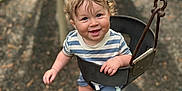Carsen joined the competition — help win amazing prizes! toddler, child, swing, playground, smile, curly_hair, outdoor, baby, blue_shorts, striped_shirt, socks, metal_chain, play, happiness, nature, fun, seat, person, young_child, daylight