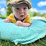 baby, child, hat, yellow_shirt, blanket, grass, outdoor, sky, blue_sky, greenery, portrait, curious, wide_eyes, soft_texture, candid, sunlight, nature, infant, toddler, cute