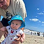 Matthew joined the competition — help win amazing prizes! adult, baby, beach, beard, blue_sky, clouds, crab_pattern, daylight, family, holding, ocean, outdoor, overalls, people, portrait, sand, shoreline, summer, sunhat, tshirt