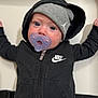 Matthew is registered to the contest to win money with this photo: baby, child, pacifier, hoodie, nike, beanie, hat, blue_eyes, infant, cute, portrait, clothing, face, expression, casual_wear, indoor, person, young, baby_girl_or_boy, closeup
