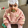 baby, child, pacifier, headband, flower, pink_sweater, carpet, toy, indoor, sitting, cute, infant, clothing, white_socks, daisy, hand, face, eyes, floor, adorable