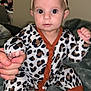 baby, infant, onesie, leopard_print, headband, bow, hand_holding, blanket, foot, sitting, indoors, person, child, cute, wide_eyes, clothing, soft_texture, portrait, baby_girl, support