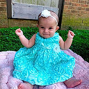 Aspyn is registered to the contest to win money with this photo: baby, child, dress, headband, flower, blue_dress, pink_blanket, grass, outdoor, brick_wall, happy, smile, barefoot, sitting, cute, infant, person, portrait, head, fingers
