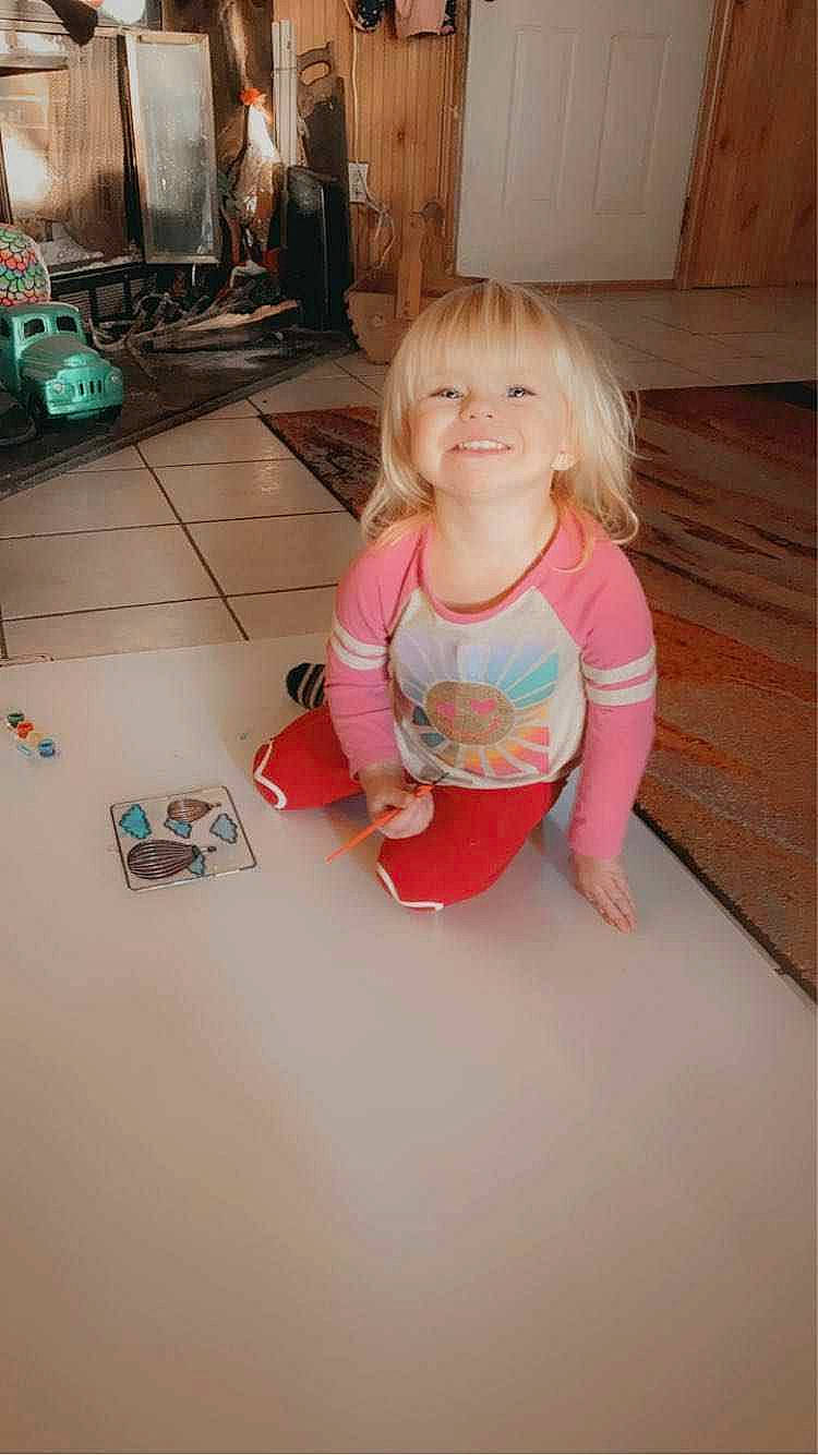 Addison is registered to the contest to win money with this photo: baby_toddler_clothing, child, floor, flooring, foot, fun, happy, hardwood, human_leg, joy, leisure, magenta, person, pink, play, room, sitting, smile, t_shirt, thigh