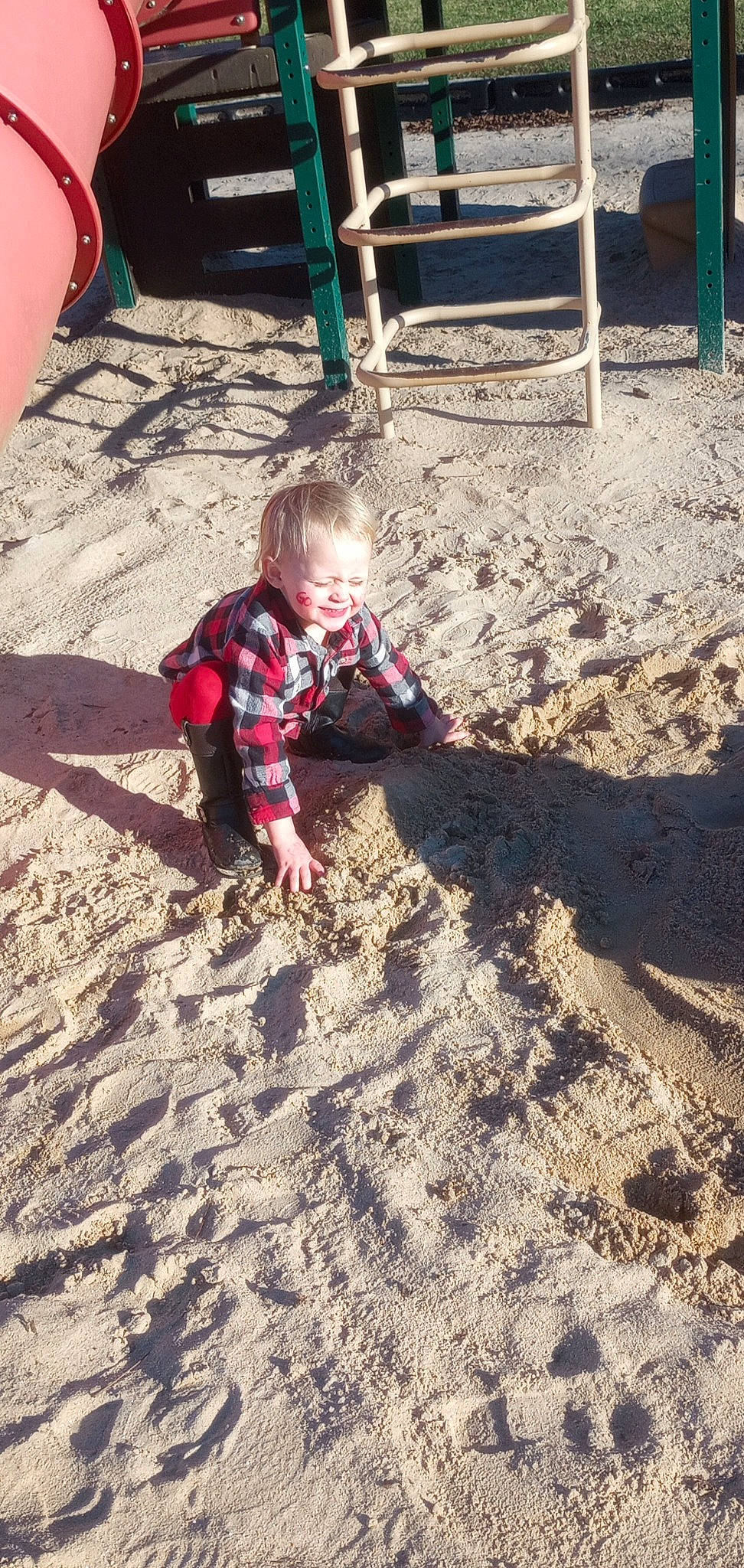 Rosanna Grace is registered to the contest to win money with this photo: asphalt, automotive_tire, baby, child, crawling, flooring, fun, grass, landscape, people_in_nature, person, recreation, road_surface, sand, shadow, sitting, soil, t_shirt, toddler, tree