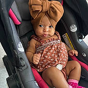 Elliani joined the competition — help win amazing prizes! baby, car_seat, headwrap, bow, dress, pink_socks, infant, child, seat_belt, patterned_clothing, cute, indoor, portrait, person, small_child, hands, legs, footwear, expression, closeup