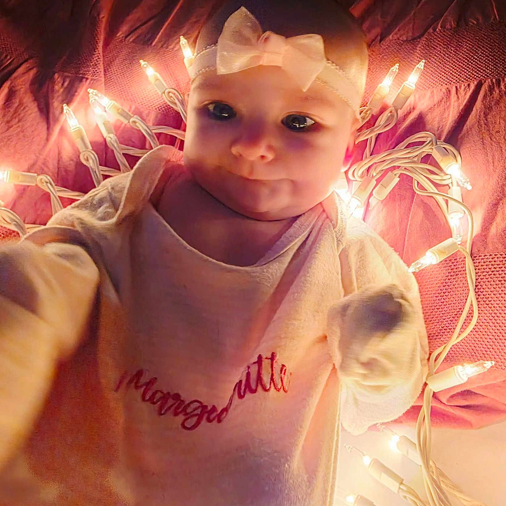 Margueritte is registered to the contest to win money with this photo: baby, baby_girl, blanket, bow, child, clothing, cozy, cute, eyes, face, headband, indoors, infant, laying_down, newborn, pink, portrait, soft_lighting, string_lights, warm_light