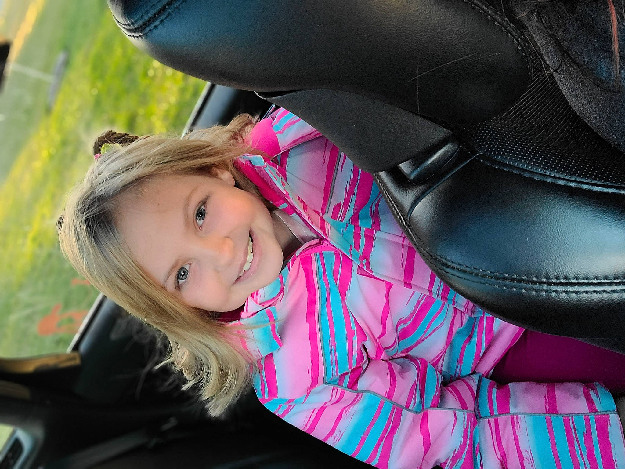 Haley is registered to the contest to win money with this photo: auto_part, automotive_design, automotive_exterior, automotive_wheel_system, comfort, fun, grass, happy, joy, leisure, lip, magenta, motor_vehicle, person, pink, plant, recreation, sitting, smile, toddler