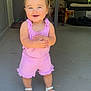 child, cute, daylight, door, floor, furniture, hair_tied, happy, home, outdoor, person, pink_clothing, porch, romper, security_sign, smiling, standing, swing, toddler, white_sandals