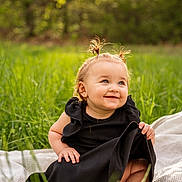 Avangeline is registered to the contest to win money with this photo: baby, black_dress, blanket, child, cute, daylight, grass, greenery, happy, nature, outdoor, pigtails, playful, portrait, sandals, sitting, smiling, sunlight, toddler, young_child