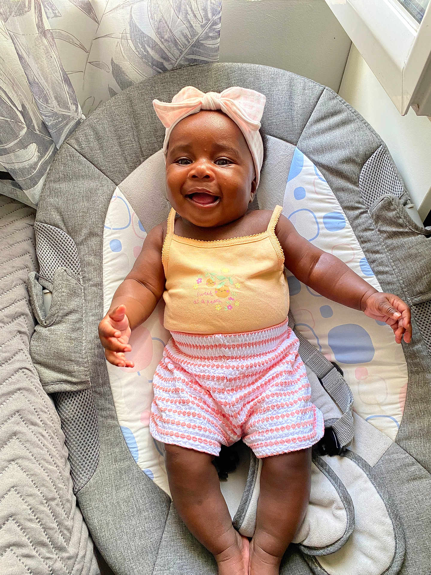 Marion a rejoint le concours — aidez-le/la à gagner de superbes lots ! baby, smiling, headband, pink_bow, baby_seat, cushion, pastel_colors, window_light, infant, clothing, shorts, tank_top, happy, indoors, child, skin, face, hands, legs, portrait