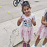 Sofia participe au concours pour gagner de l'argent avec cette photo : child, girl, winking, peace_sign, pink_dress, tutu, minnie_mouse, outdoor, sidewalk, bicycle, people, group, casual_clothing, playful, smile, hair_tie, sneakers, daylight, fun, urban