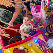 Tiago Jourdain participe au concours pour gagner de l'argent avec cette photo : child, adult, amusement_ride, toy_car, pink_swan, indoor_playground, puzzle_floor, colorful, steering_wheel, person, ride, fun, play, family, woman, curious_expression, seat, entertainment, kid, bright