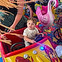 child, adult, amusement_ride, toy_car, pink_swan, indoor_playground, puzzle_floor, colorful, steering_wheel, person, ride, fun, play, family, woman, curious_expression, seat, entertainment, kid, bright