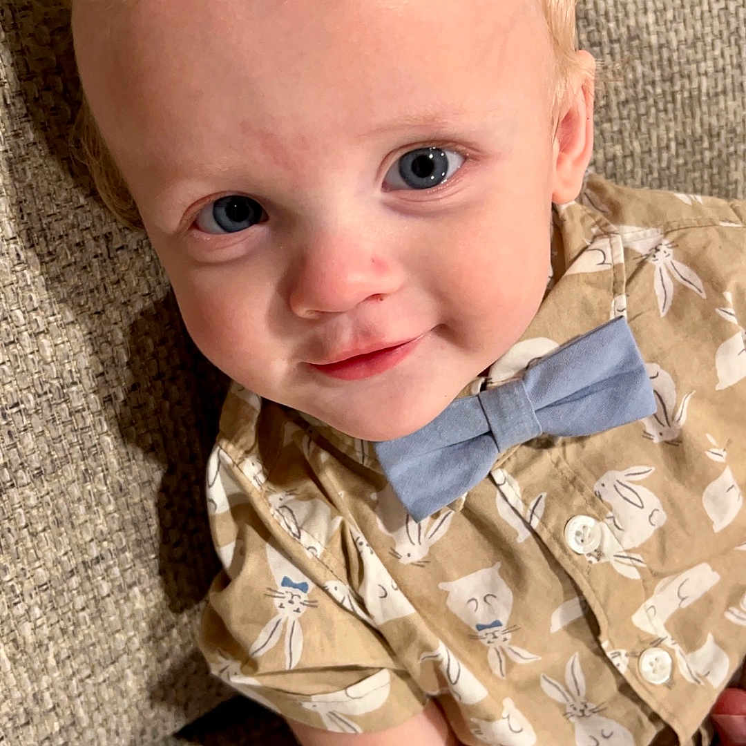 Maveryk is registered to the contest to win money with this photo: accessories, baby, blonde, clothing, couch, dress, face, formalwear, furniture, hair, happy, head, person, photography, portrait, sitting, sleeve, smile, t_shirt, tie