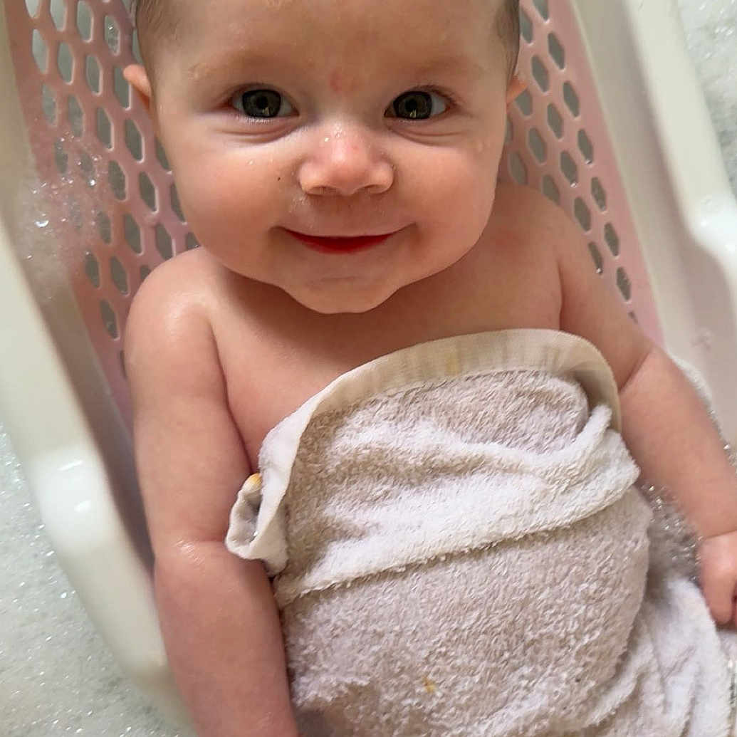 Aurora-Jayne joined the competition — help win amazing prizes! arm, baby, bath, bubbles, child, closeup, cute, face, happy, indoors, infant, leg, person, pink_bath_seat, portrait, skin, smiling, towel, water, wet_hair