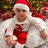 Pasha joined the competition — help win amazing prizes! baby, infant, santa_hat, christmas_tree, christmas_lights, presents, holiday, festive, red_clothing, white_clothing, pillow, animal_print, smiling, indoors, celebration, cute, child, seasonal, decorations, happy
