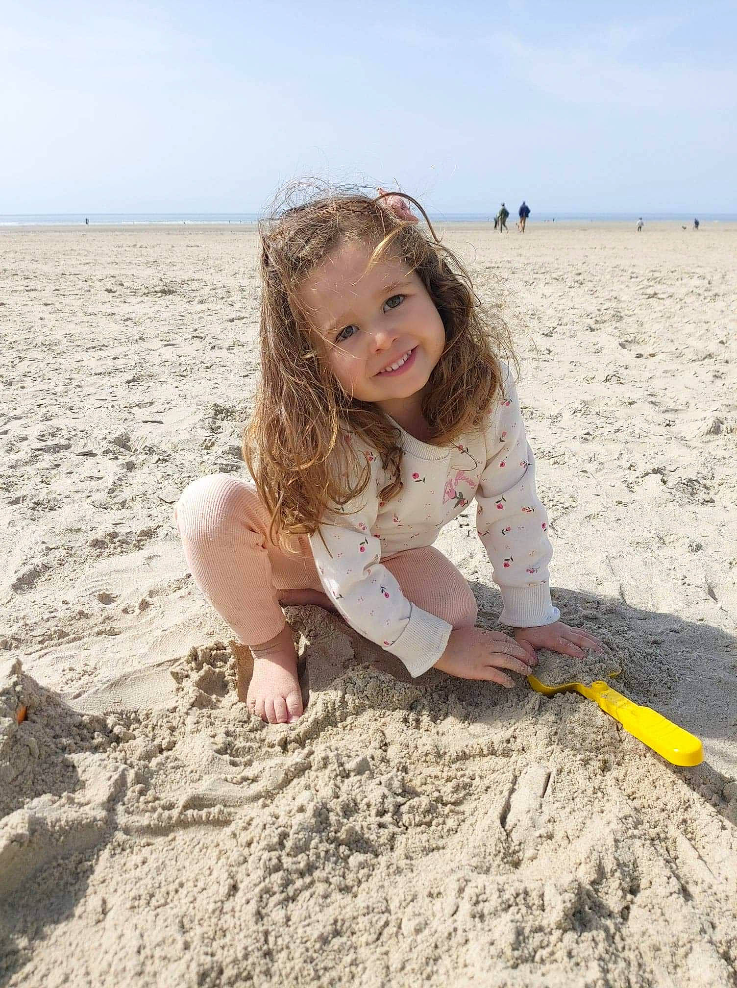 Romy a rejoint le concours — aidez-le/la à gagner de superbes lots ! beach, blond, body_of_water, child, coast, ecoregion, fun, happy, joy, landscape, natural_environment, people_in_nature, person, sand, shore, sitting, sky, smile, soil, summer