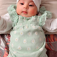 Aayat is registered to the contest to win money with this photo: adorable, baby, bow, child, cute, face, floral_pattern, green_clothing, headband, indoors, infant, long_sleeves, lying_down, person, portrait, small, smiling, soft_surface, white_clothing, young_child