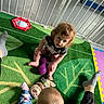 Enzo joined the competition — help win amazing prizes! toddler, child, toy, playmat, curly_hair, baby, indoor, floor, gate, sock, plush_toy, patterned_clothing, colorful, crawling, playtime, carpet, green, purple_toy, sitting, feet