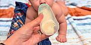Sonny is registered to the contest to win money with this photo: baby, bottle, feeding, hand, blanket, striped_blanket, infant, face, eyes, mouth, skin, person, indoor, crawling, young_child, cute, focus, comfort, care, nurturing