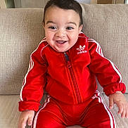 Jayden Winstersheim a rejoint le concours — aidez-le/la à gagner de superbes lots ! baby, child, smiling, red_tracksuit, adidas, sitting, couch, indoor, happy, face, young_child, clothing, portrait, cute, infant, person, sleeves, hands, jacket, pants