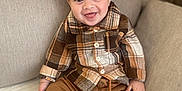 Jayden Winstersheim a rejoint le concours — aidez-le/la à gagner de superbes lots ! toddler, child, smile, plaid_shirt, brown_pants, boots, cap, couch, indoors, happy, seated, cozy, fashion, portrait, cute, baby, clothing, face, person, home