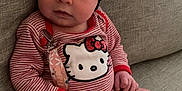 Jade is registered to the contest to win money with this photo: baby, infant, child, headband, flower, onesie, hello_kitty, pacifier, clip, socks, couch, sofa, fabric, striped_clothing, cute, sitting, indoors, portrait, soft_lighting, curious