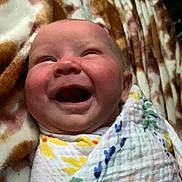 Jade is registered to the contest to win money with this photo: baby, smiling, laughing, blanket, swaddle, face, infant, cozy, pattern, floral, wrapped, happy, child, cute, skin, newborn, indoor, soft, comfort, portrait