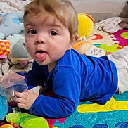 Mason joined the competition — help win amazing prizes! baby, child, blue_shirt, diaper, play_mat, plush_toys, blanket, colorful, indoor, cute, tongue_out, curious, lying_down, hand, face, person, soft_toys, floor, home, smile