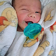 Corey joined the competition — help win amazing prizes! baby, pacifier, blanket, winking, face, infant, child, cozy, soft_texture, cute, wrapped, playful, close_up, indoor, comfort, smile, head, skin, warm, resting
