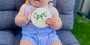 Marius a rejoint le concours — aidez-le/la à gagner de superbes lots ! baby, barefoot, blue_striped_clothing, child, cute, daylight, grass, gray_chair, happy, holding_sign, infant, one_person, outdoor, person, plush_chair, portrait, sign, sitting, smiling, young_child