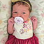 baby, infant, pacifier, headband, bow, dress, floral_pattern, tulle_skirt, hand, face, lying_down, blanket, cute, child, newborn, portrait, indoors, clothing, soft, expression