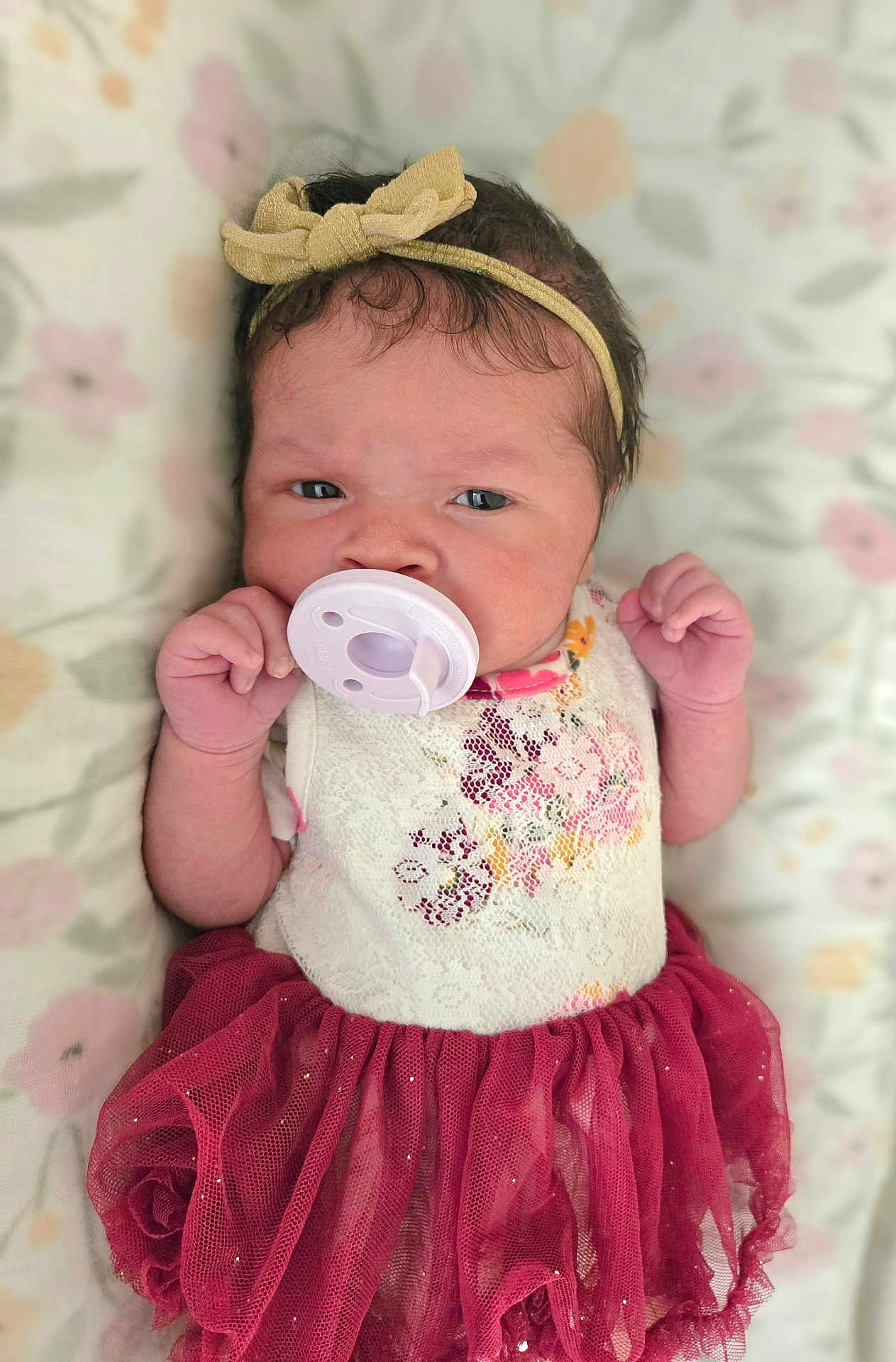 Nariah Alaia Rene' joined the competition — help win amazing prizes! baby, infant, pacifier, headband, bow, dress, floral_pattern, tulle_skirt, hand, face, lying_down, blanket, cute, child, newborn, portrait, indoors, clothing, soft, expression