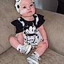 baby, child, infant, headband, mickey_mouse, clothing, shoes, socks, face, medical_tape, couch, furniture, sitting, indoor, cute, portrait, polka_dot, young_child, person, apparel