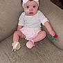 baby, infant, child, headband, pink, toy, couch, footwear, medical_tape, indoor, cute, clothing, sitting, expression, face, person, furniture, carpet, home, young