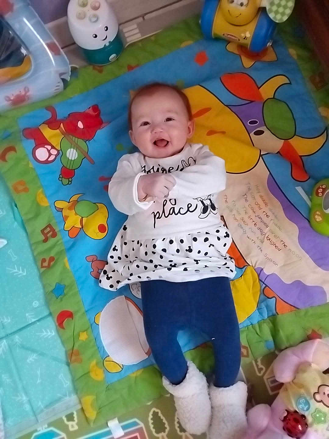 Ambre a rejoint le concours — aidez-le/la à gagner de superbes lots ! baby, child, smiling, play_mat, toy, colorful, indoor, clothing, footwear, happy, person, infant, cute, patterned, lying_down, plush_toy, decor, floor, warm_clothes, expression