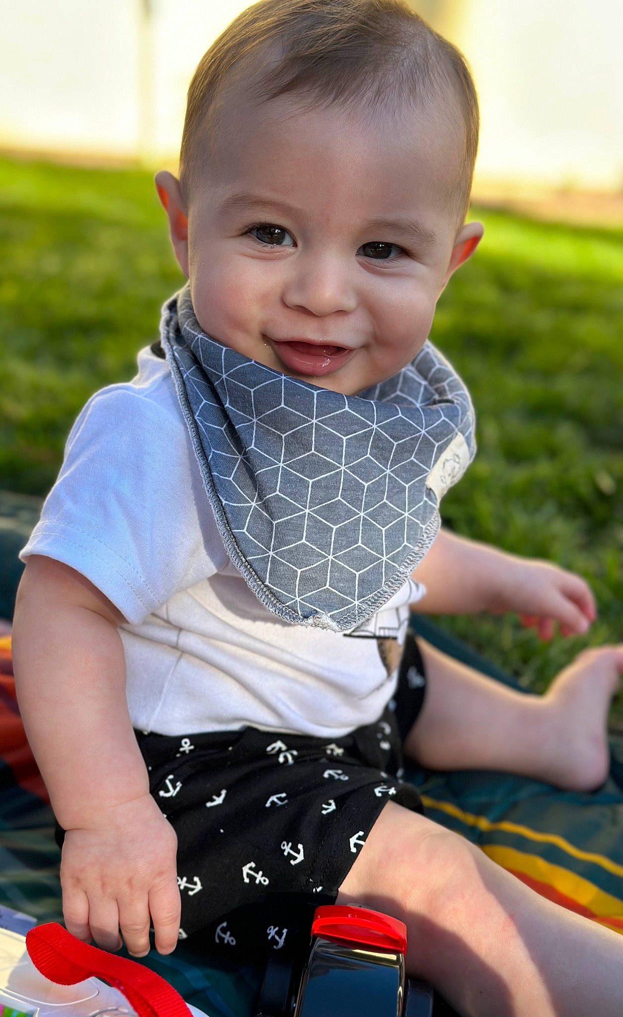Raylan is registered to the contest to win money with this photo: arm, baby, baby_toddler_clothing, child, fun, grass, happy, leisure, pattern, people_in_nature, person, personal_protective_equipment, plaid, recreation, sitting, skin, sleeve, smile, summer, thigh