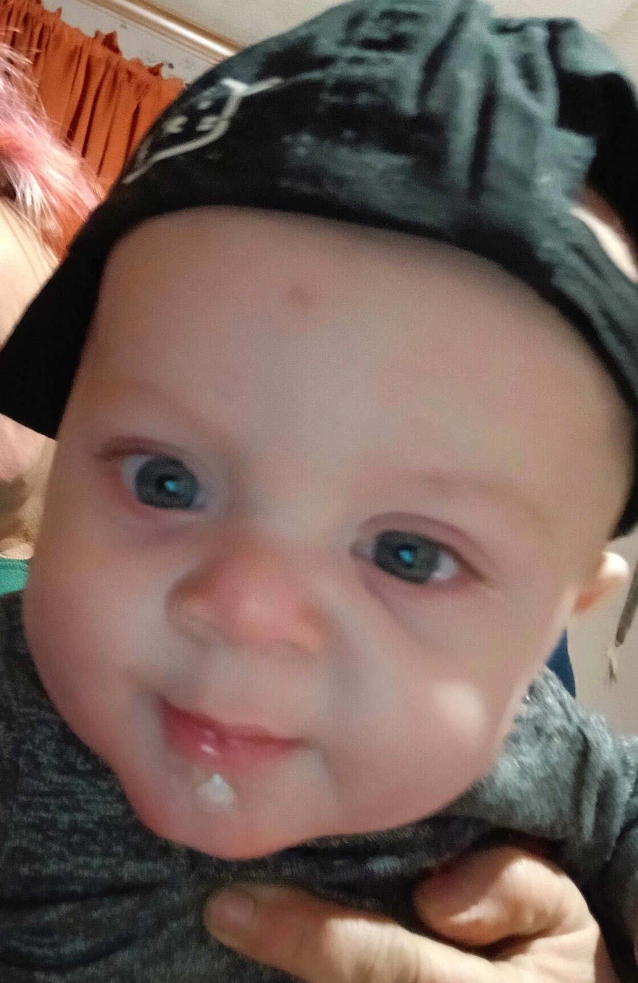 Jordan is registered to the contest to win money with this photo: baby, infant, face, cap, drool, hand, person, closeup, blue_eyes, skin, clothing, indoor, curious, child, headwear, portrait, young, human, expression, casual