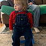 child, toddler, blond_hair, overalls, red_shirt, sitting, blue_stool, living_room, couch, seated_adult, socks, carpet, rug, portrait, profile_view, cozy, knit_blanket, denim, curious, indoor