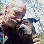 Bentley is registered to the contest to win money with this photo: elderly_man, dog, outdoor, trees, sky, affection, companionship, portrait, close_up, nature, friendship, smiling, beard, hand, casual_clothing, sunlight, happy, pet, animal, human