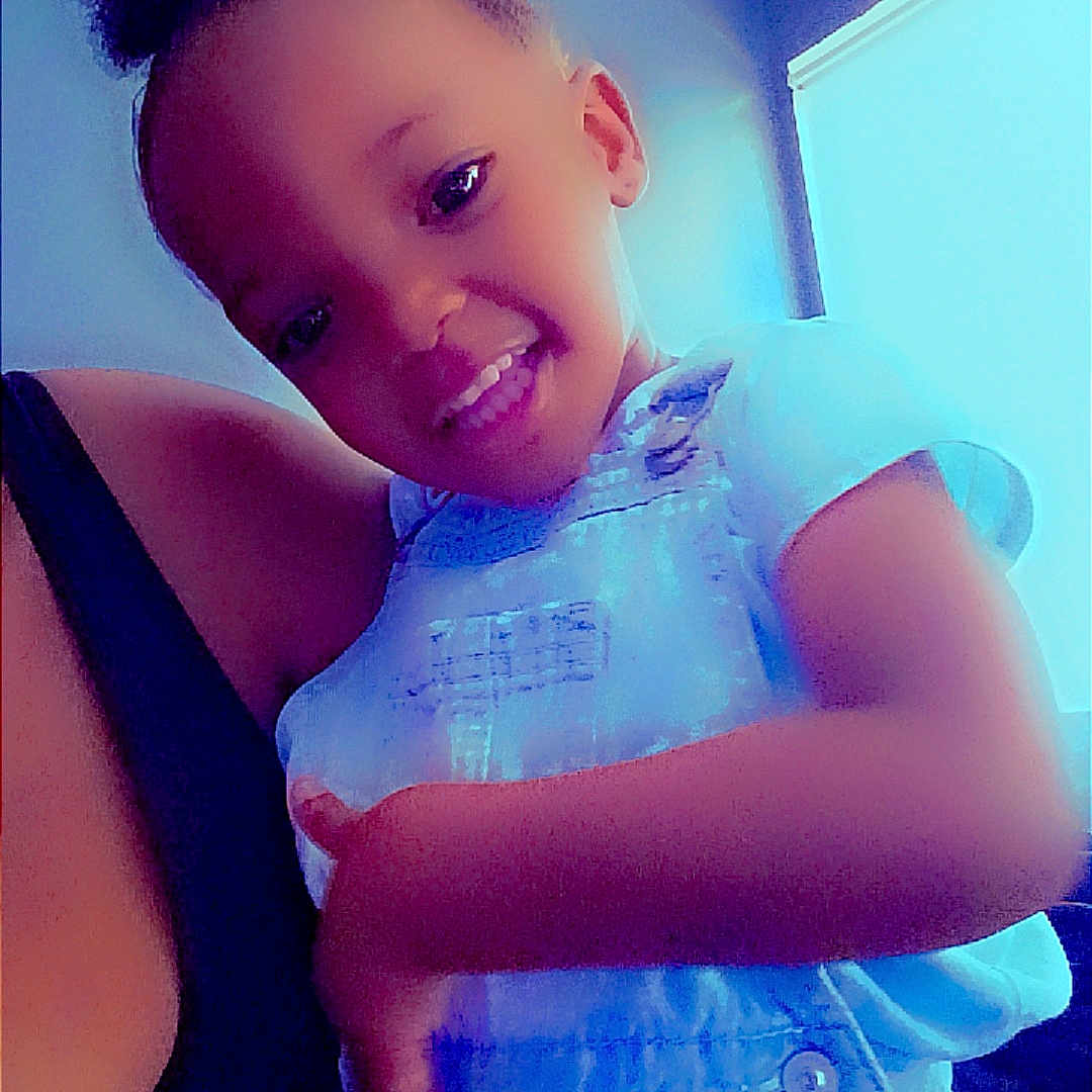 Julia joined the competition — help win amazing prizes! child, toddler, smiling, indoor, person, hair_puff, holding, denim_overalls, short_sleeve, face, happy, cute, family, portrait, skin, hand, arm, casual_clothing, home, window