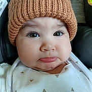 Duker joined the competition — help win amazing prizes! baby, infant, face, hat, knitted_hat, white_clothing, car_seat, pout, expression, chubby_cheeks, close_up, child, cute, young_child, indoor, seat, safety_label, portrait, person, headwear