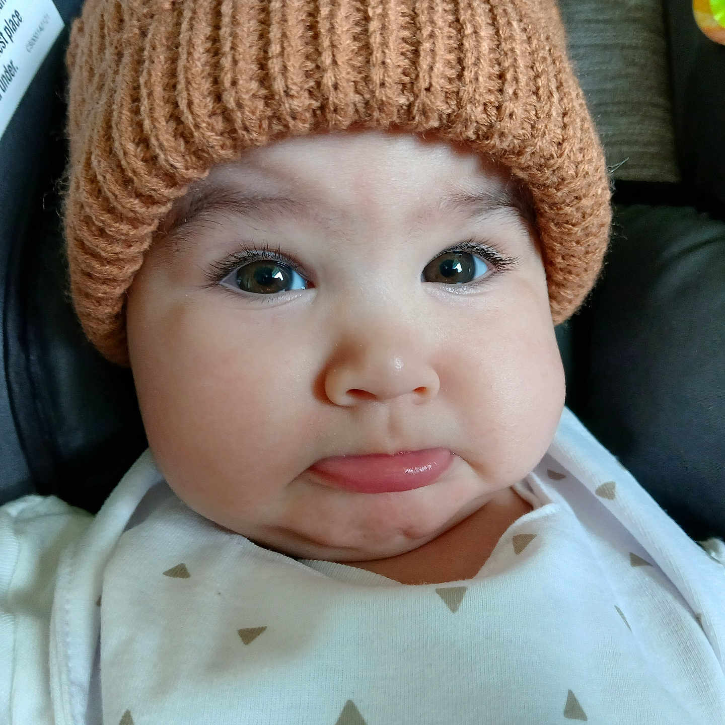 Duker joined the competition — help win amazing prizes! baby, car_seat, child, chubby_cheeks, close_up, cute, expression, face, hat, headwear, indoor, infant, knitted_hat, person, portrait, pout, safety_label, seat, white_clothing, young_child