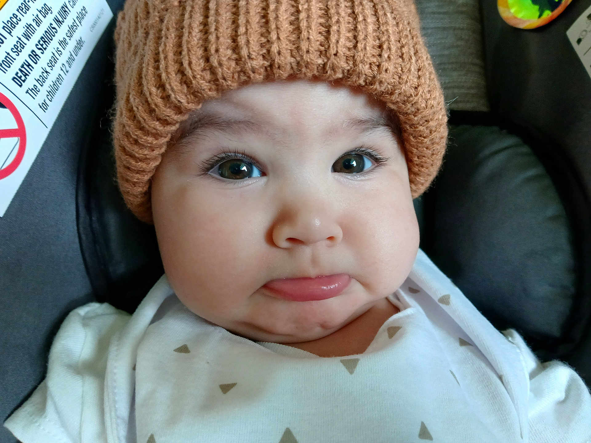 Duker joined the competition — help win amazing prizes! baby, infant, face, hat, knitted_hat, white_clothing, car_seat, pout, expression, chubby_cheeks, close_up, child, cute, young_child, indoor, seat, safety_label, portrait, person, headwear